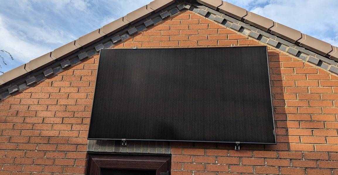 A solar panel on a wall, low sun is hitting most of the panel.